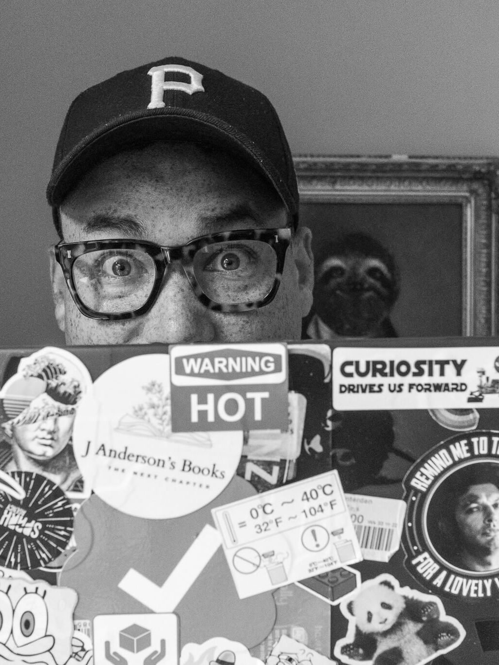 Sam, founder of AASSCC, peering over a sticker-covered laptop